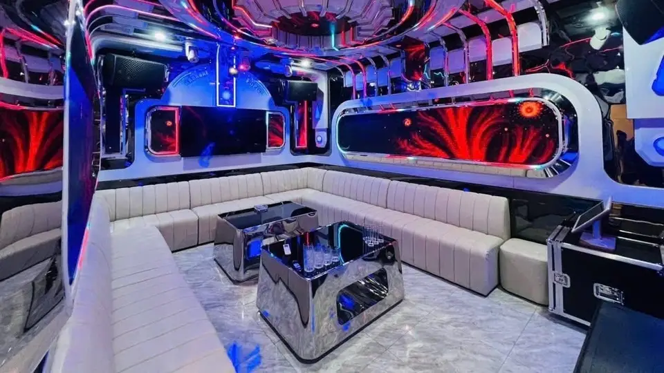 Dubai Karaoke lounge room featuring white leather sofas, a mirrored corner table, and a red-blue LED patterned ceiling
