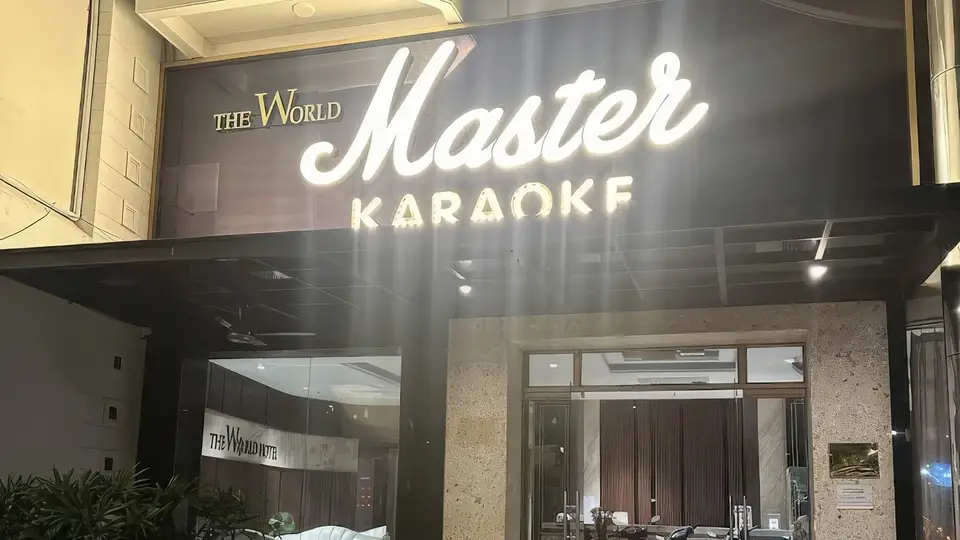 ゴールドカラーの「Master Karaoke」ネオンサインと大理石の外壁、ガラスドアが印象的なマスター カラオケ正面玄関の全景