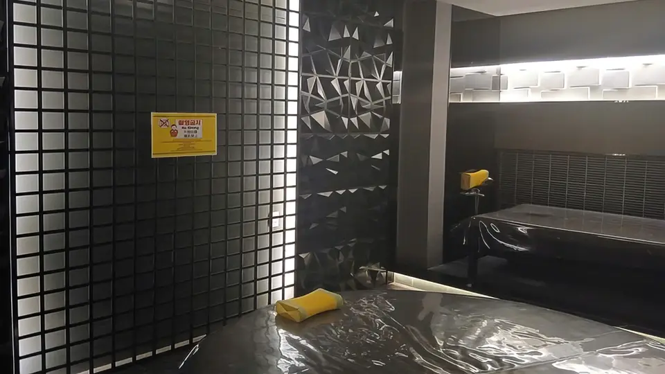 Interior view of Now Spa with glass block walls, diamond pattern panels, and a black oil massage bed