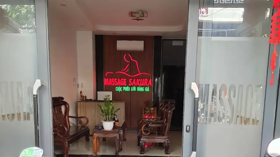 Sakura Massage entrance with red neon lighting and traditional wooden chairs in the welcome area