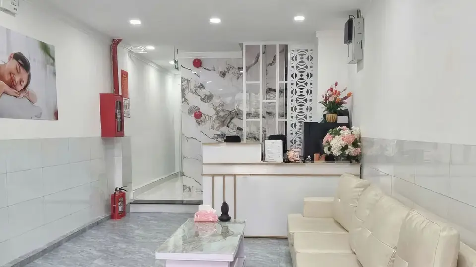 White-toned lobby space, marble-patterned walls, reception counter, and cream-colored sofa waiting area