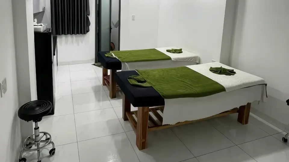 Two massage beds on a clean tiled floor, decorated with green blankets and neatly folded towels