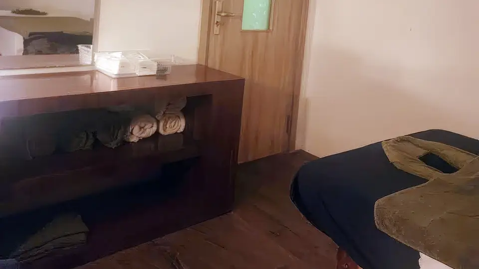 Cozy and quiet private room interior with wooden cabinets, rolled towels, and a massage bed